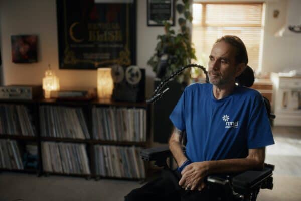 Chris Kemp sits in his living room in a power chair