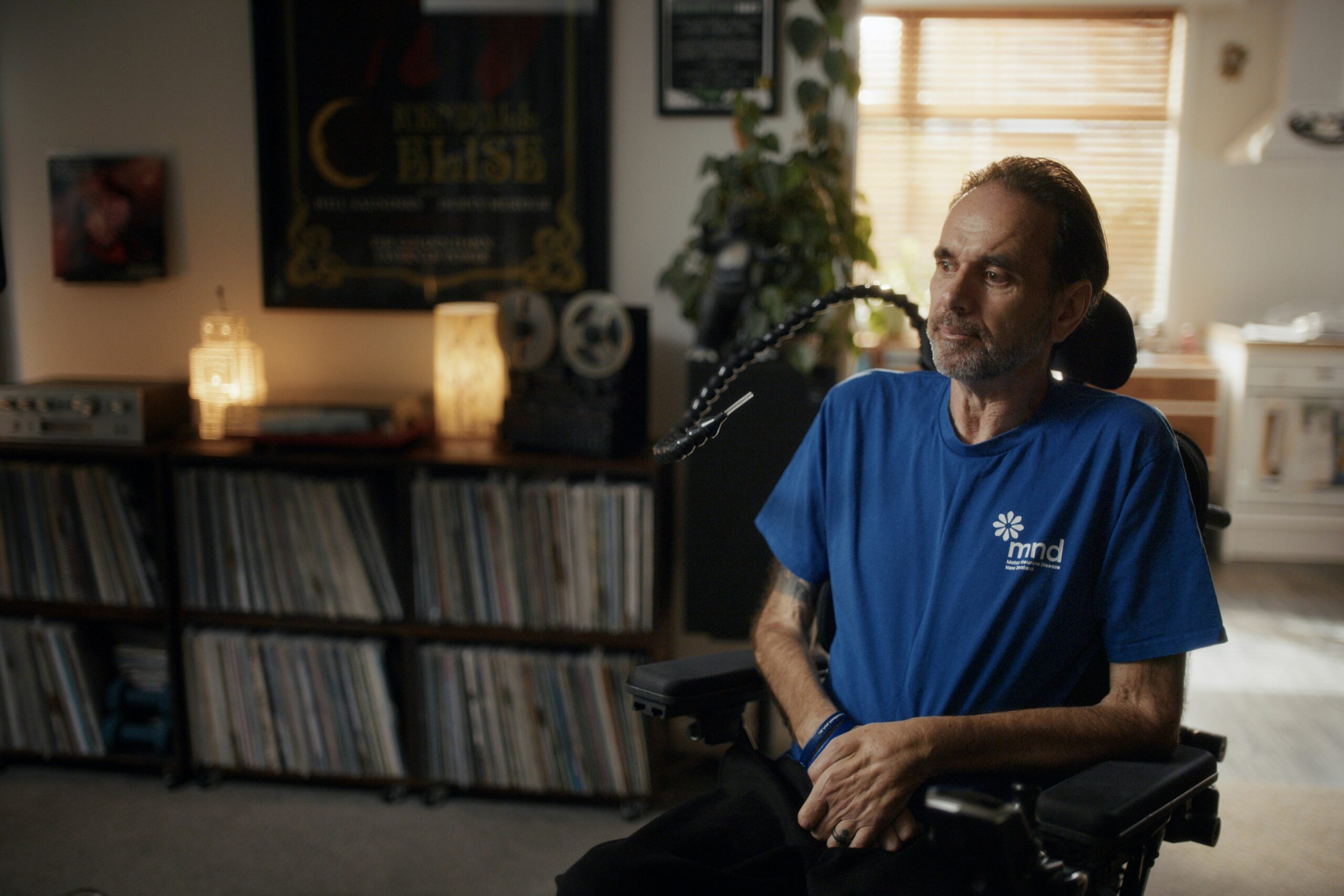 Chris Kemp sits in his living room in a power chair