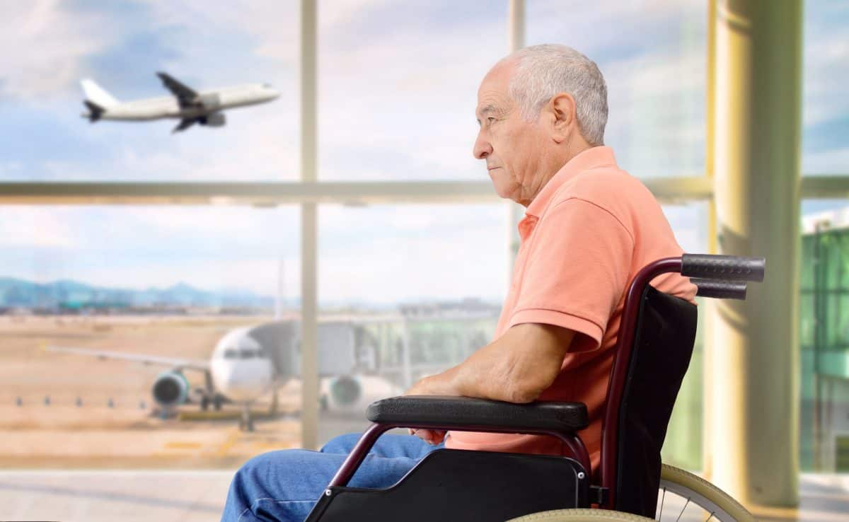 senior on a wheelchair at a airport looking outside
