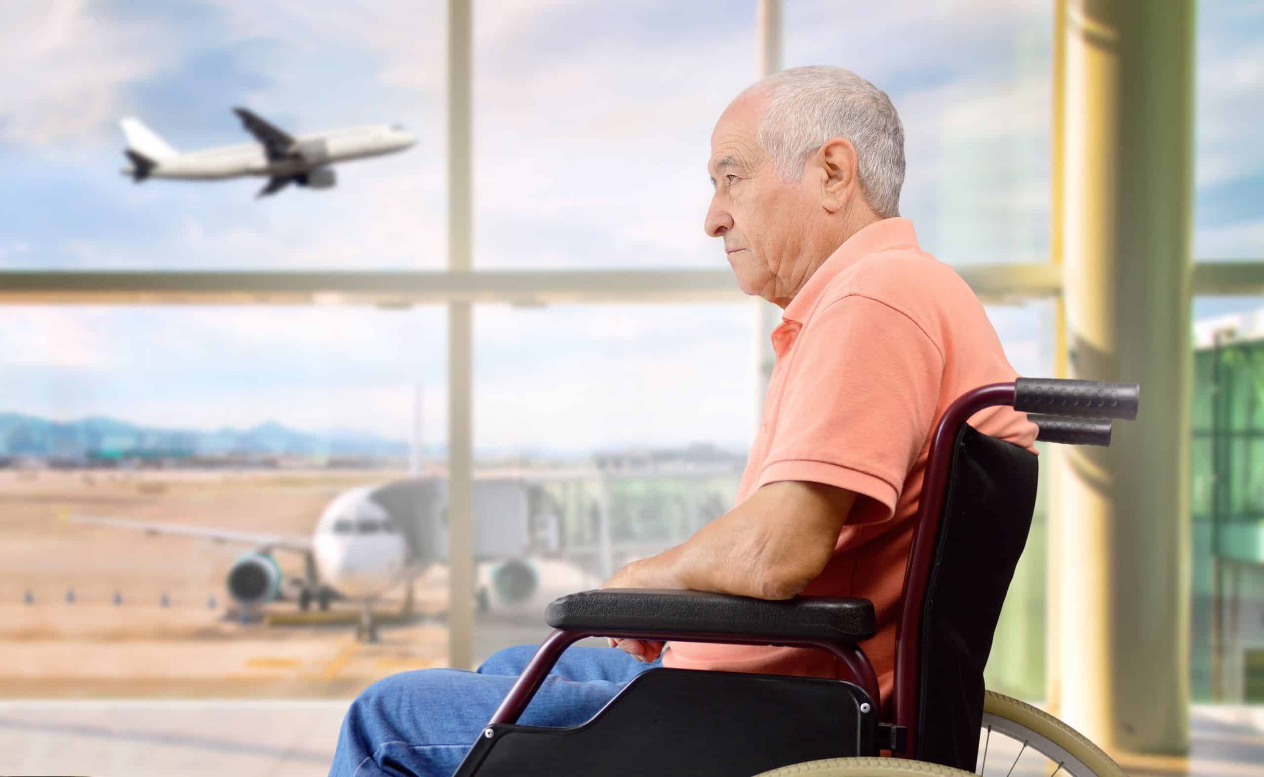 senior on a wheelchair at a airport looking outside